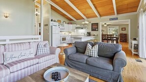 A cozy living room with a grey sofa and a striped couch, a wooden coffee table with a tray, and a kitchen area with white cabinets and a sign reading "Ski Trails". - Mountain Retreat Near Bryce Resort. Game Rm. Sleeps 8 Family and Dog Friendly! (Basye)