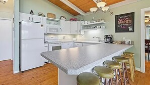 A modern kitchen with white cabinets, a granite island with stools, a chalkboard with a welcome message, and wooden ceiling beams. - Mountain Retreat Near Bryce Resort. Game Rm. Sleeps 8 Family and Dog Friendly! (Basye)