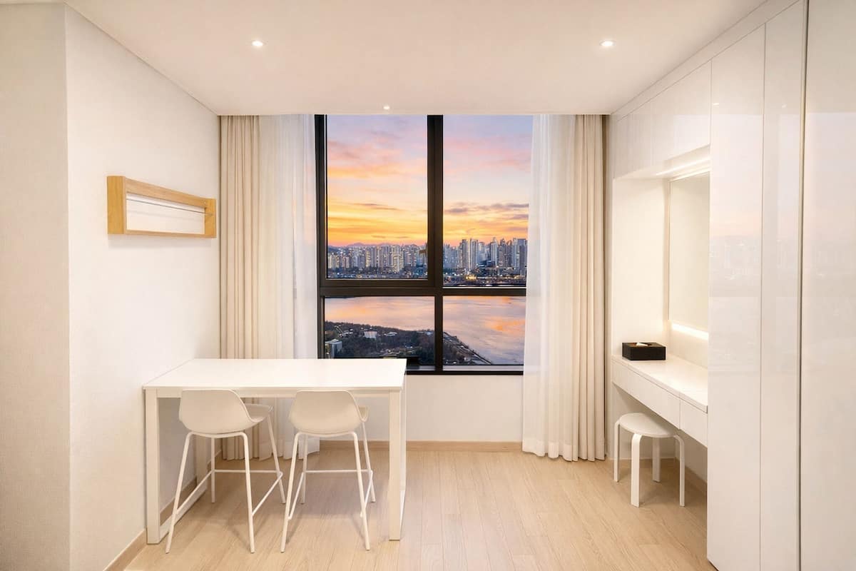 A modern room with a large window, a white desk, two white chairs, and a small stool.