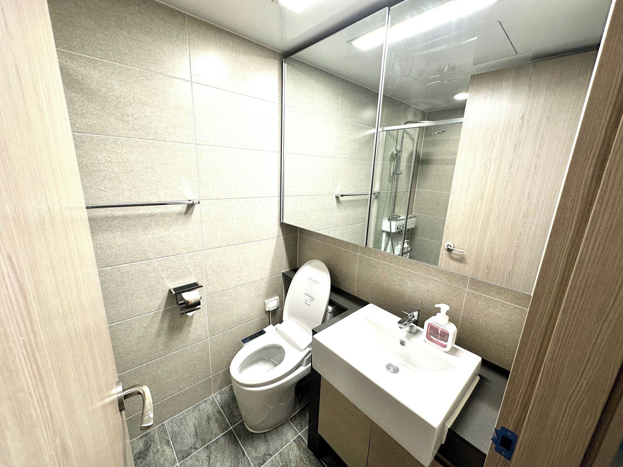 Une salle de bain moderne avec des toilettes, un lavabo et un miroir.