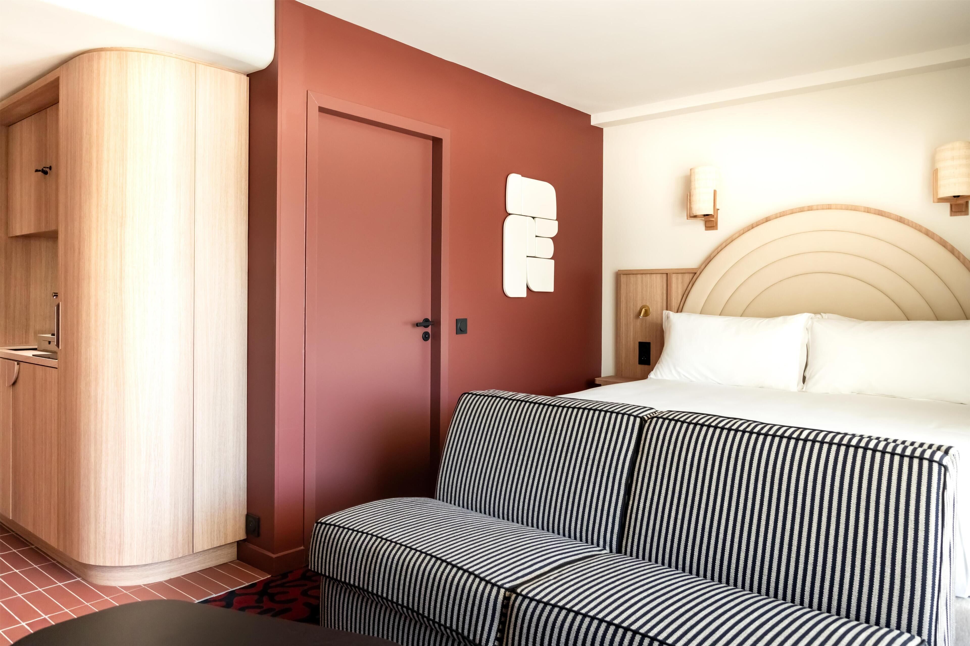 Ett hotellrum med en säng, en soffa, en garderob och en dörr.