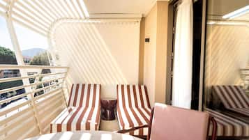 A balcony with striped chairs, a table, and a coffee machine.