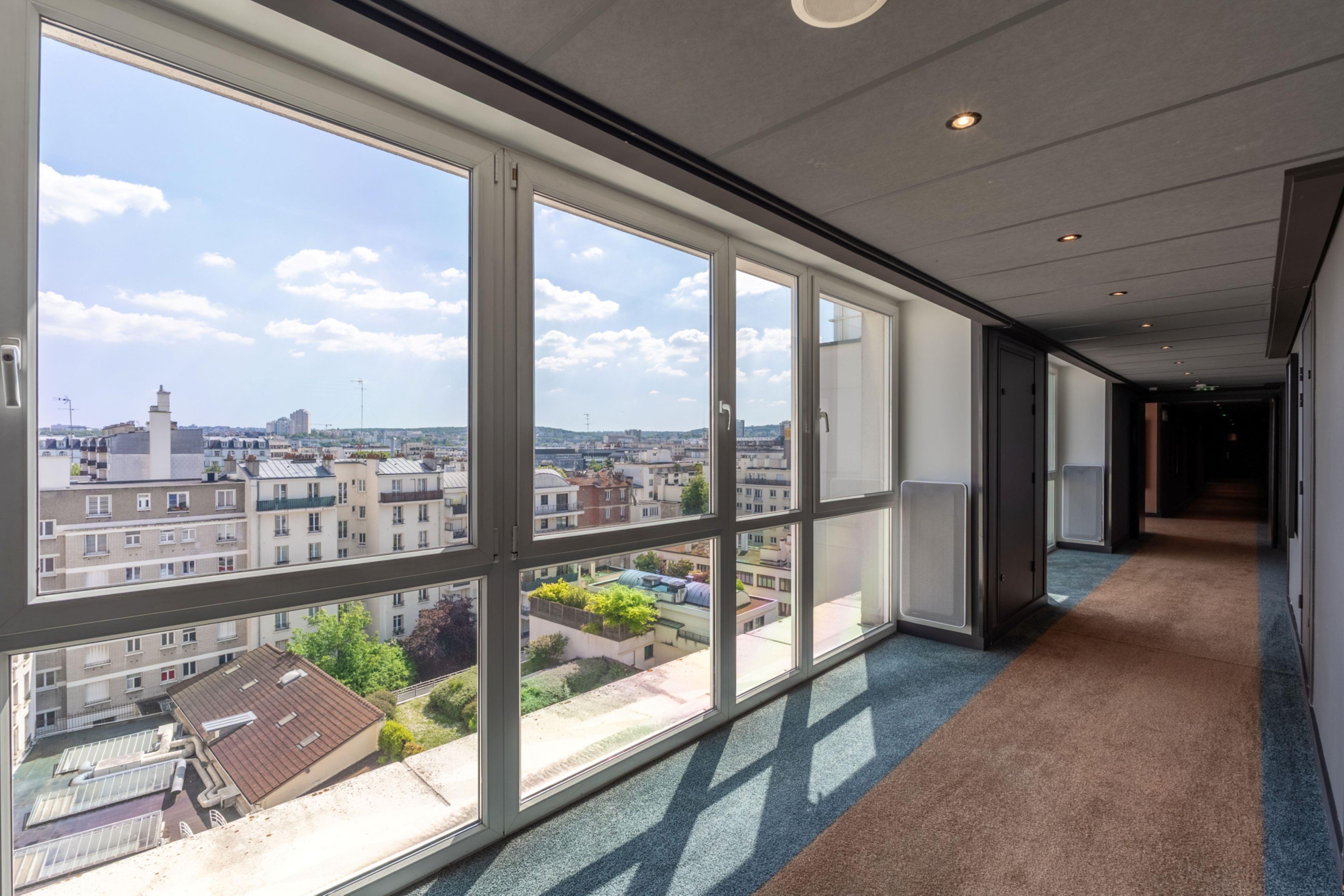 A corridor with large windows offering views of a cityscape.