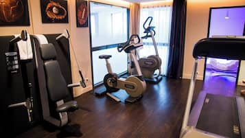 Ein Heimfitnessraum mit Laufband, Ergometer und einer Gewichtshalterung.