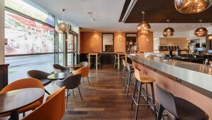 A modern bar area with a long counter, multiple bar stools, and pendant lighting.