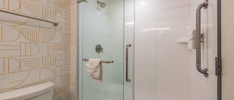 Ein modernes Badezimmer mit einer Duschkabine aus Glas, einer Toilette und einer Wand mit Muster.