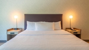 Habitación de hotel con cama, dos mesitas de noche y una pared con patrón de espiga.