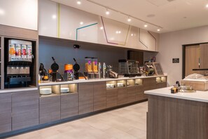 A modern breakfast bar with waffle makers, a coffee machine, and a juice dispenser. - Home2 Suites By Hilton North Attleboro (North Attleboro)