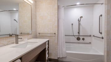 A modern bathroom with a double sink vanity, a walk-in shower with grab bars, and a large mirror.
