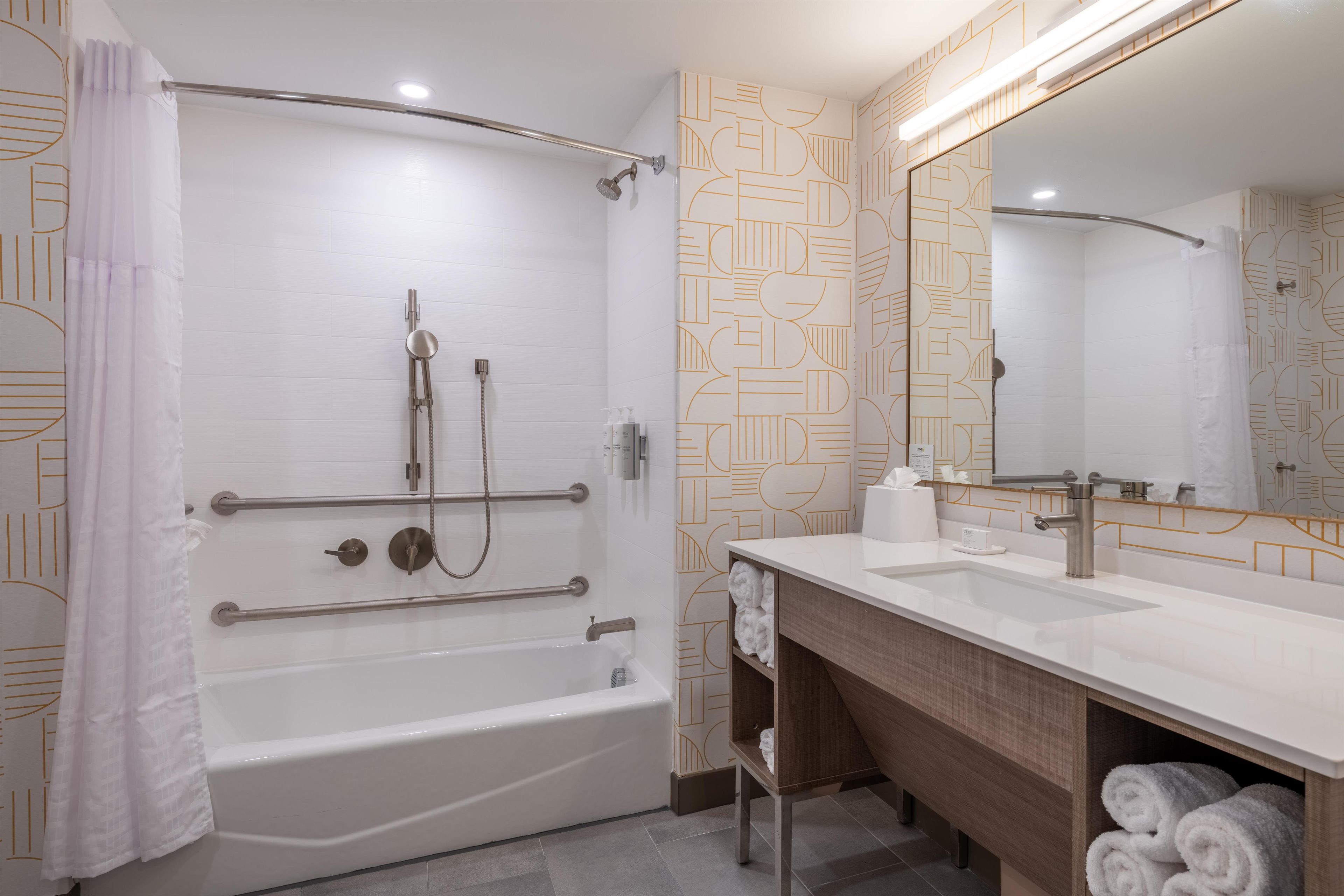 Une salle de bain moderne avec une douche à l’italienne, un meuble-lavabo avec miroir et une baignoire.