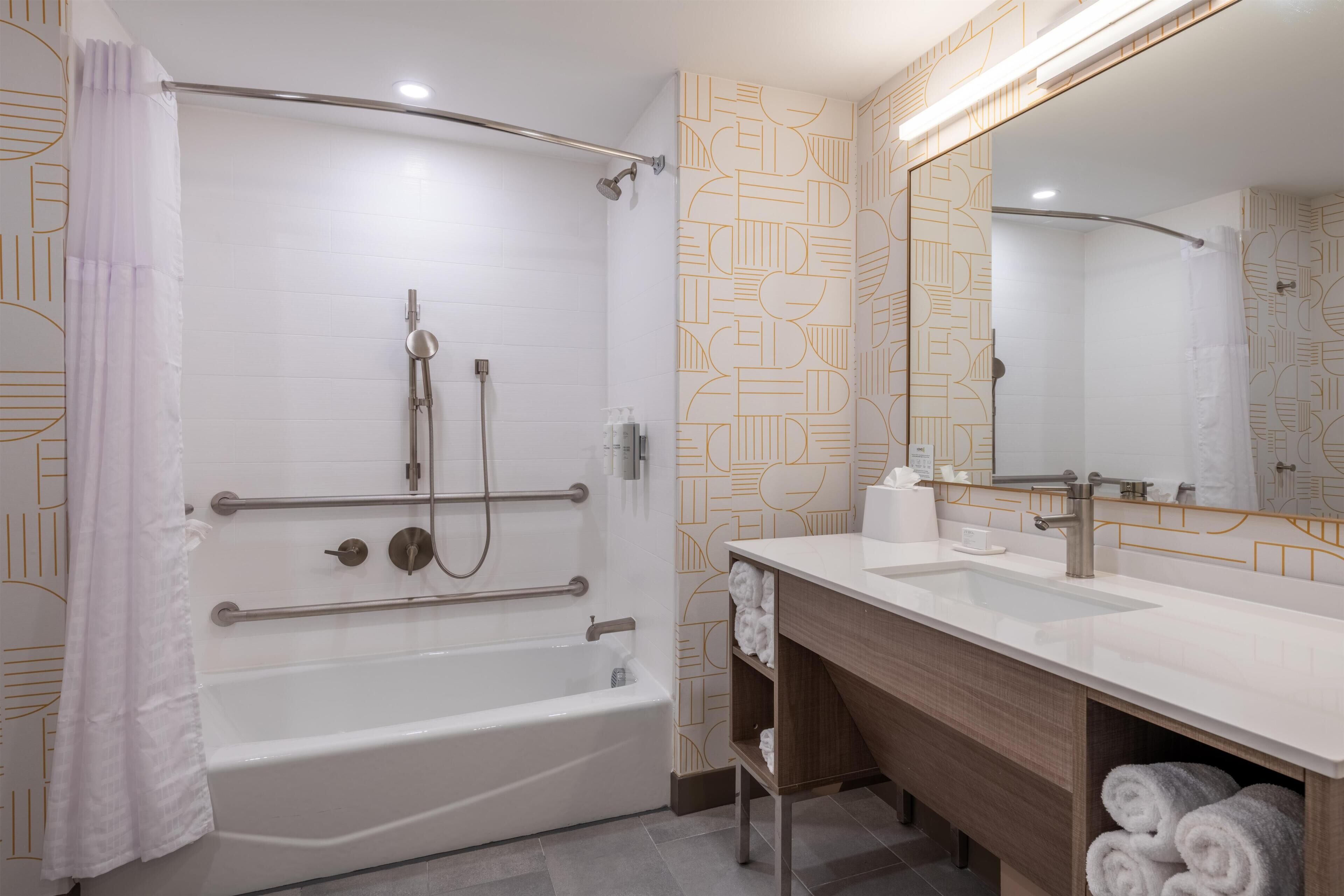A modern bathroom with a walk-in shower, a vanity with a mirror, and a bathtub.