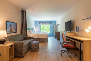 Une chambre d’hôtel comprenant un lit, un bureau, une chaise, un canapé et un téléviseur.