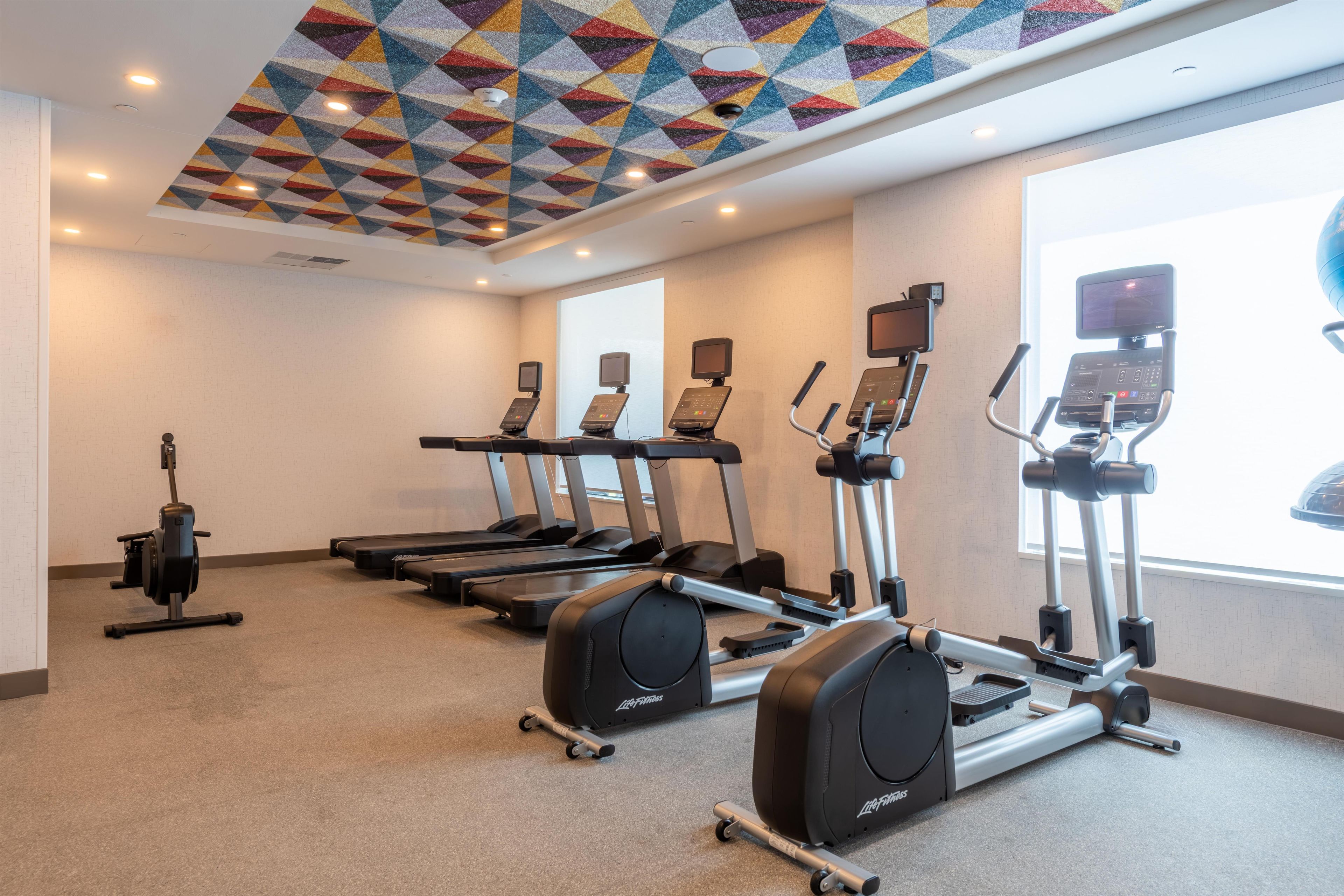 A gym with treadmills, elliptical machines, and a stationary bike.