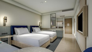 Ein Hotelzimmer mit zwei Betten, einem Badezimmer mit großem Spiegel und einem an der Wand befestigten Fernseher.