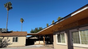 Ein modernes Haus mit Pool, Palmen und einer überdachten Terrasse.