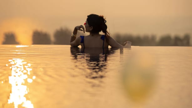 A person in a swimming pool with a sunset in the background.