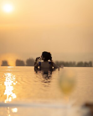 A person in a swimming pool with a sunset in the background. - Hilton Garden Inn Goa Calangute (Calangute)
