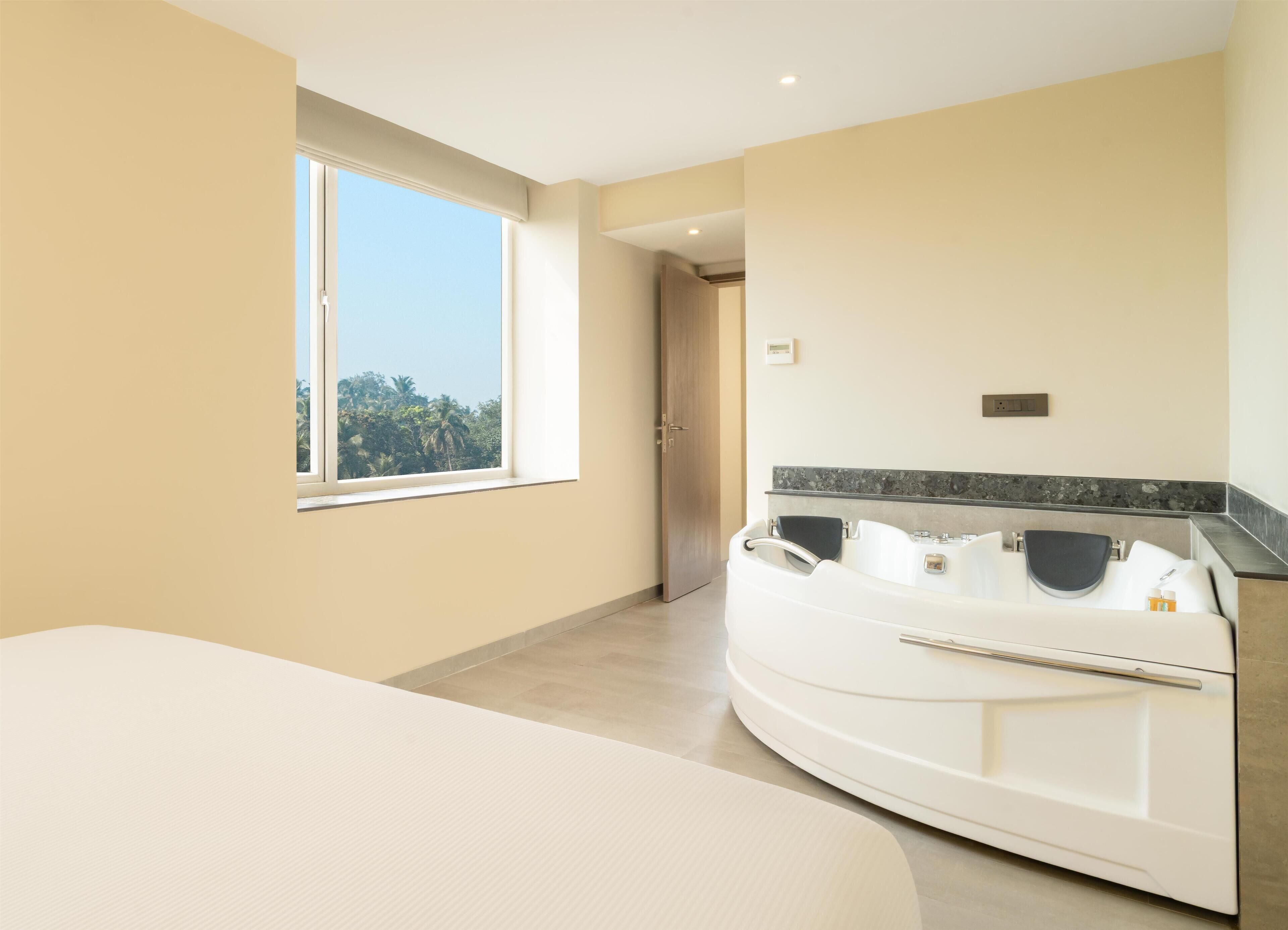 Een moderne badkamer met een ruim bad, een douchegedeelte en een raam met uitzicht op palmbomen.
