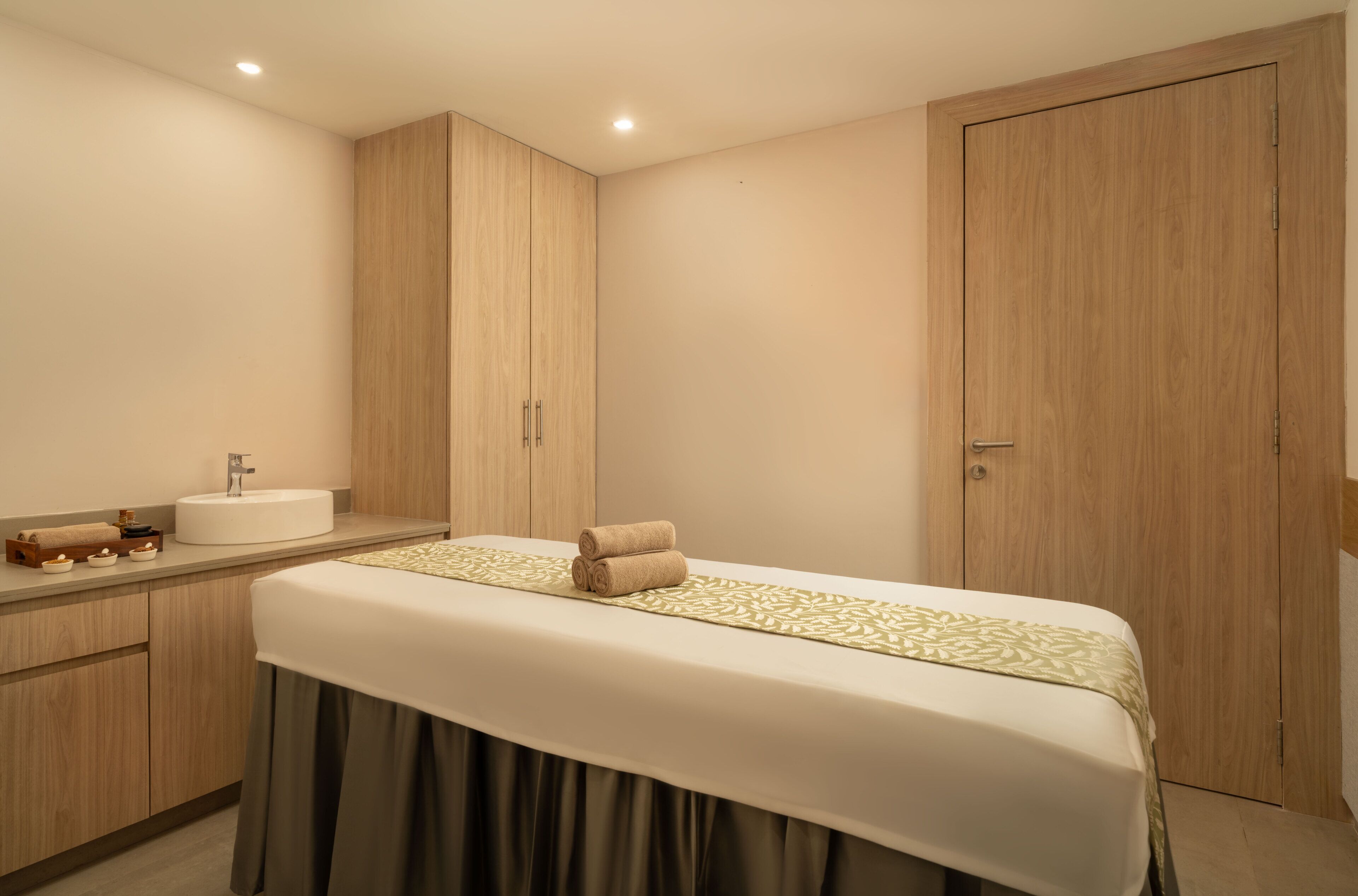 A hotel room with a bed, a sink, and wooden cabinets.