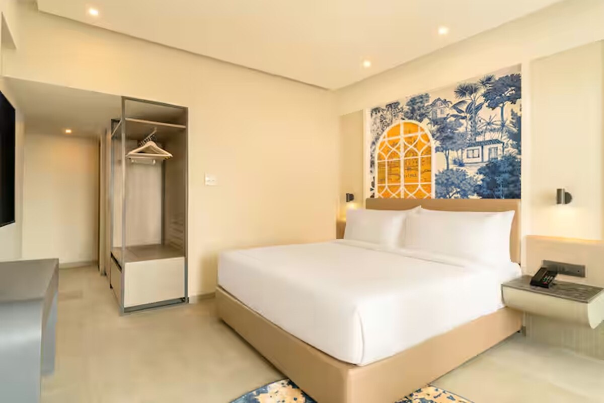 Una habitación de hotel con cama, armario, mesita de noche y una pared con diseño azul y blanco.