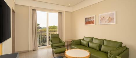 A modern living room with a green sofa, a round wooden table, and a TV.