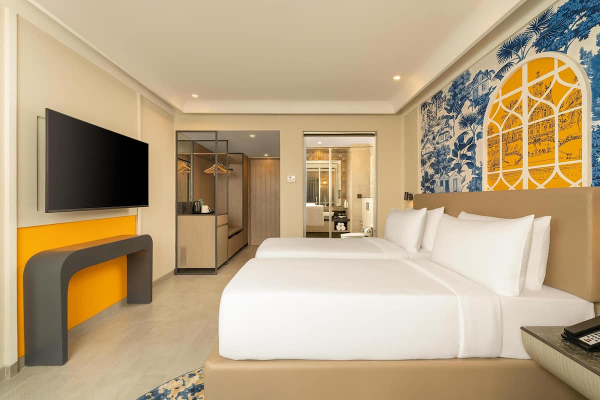 A hotel room with a bed, a TV, a bathroom, and a wardrobe.