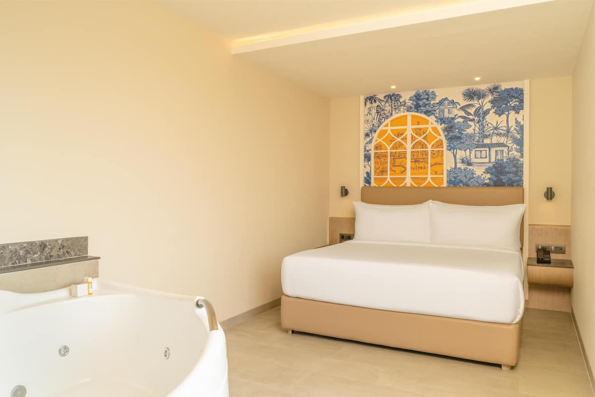 A bedroom with a large bed, a bathtub, and a wall mural.