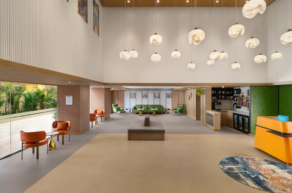 A spacious lobby with a reception desk, seating area, and a green sofa. - Hilton Garden Inn Goa Calangute (Calangute)