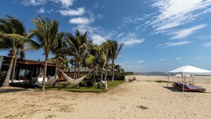 Un resort frente al mar con palmeras, una hamaca y sillas de playa.