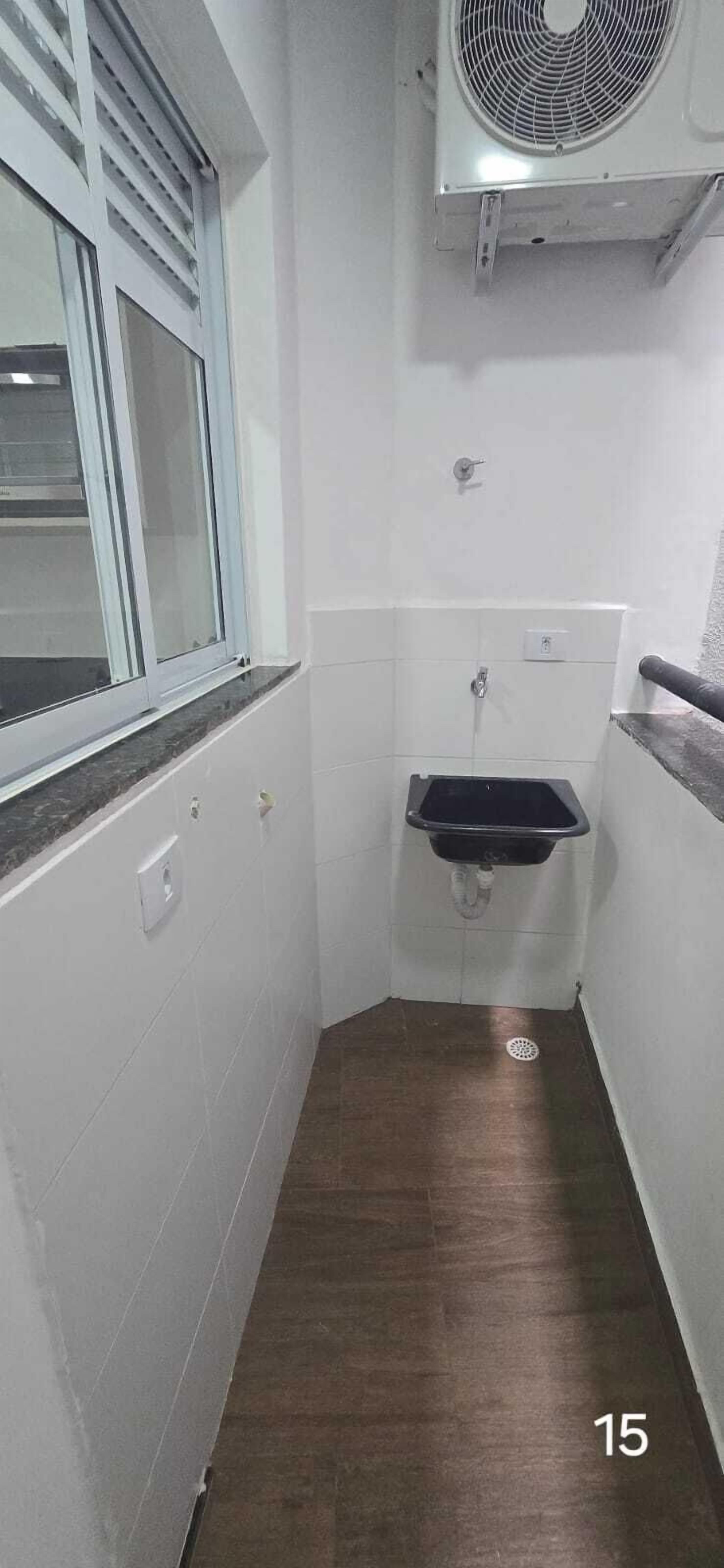 Un bagno stretto con una finestra, un lavandino e una ventola.