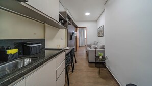 Cozinha moderna com forno embutido, pia e área de jantar com mesa e cadeiras.
