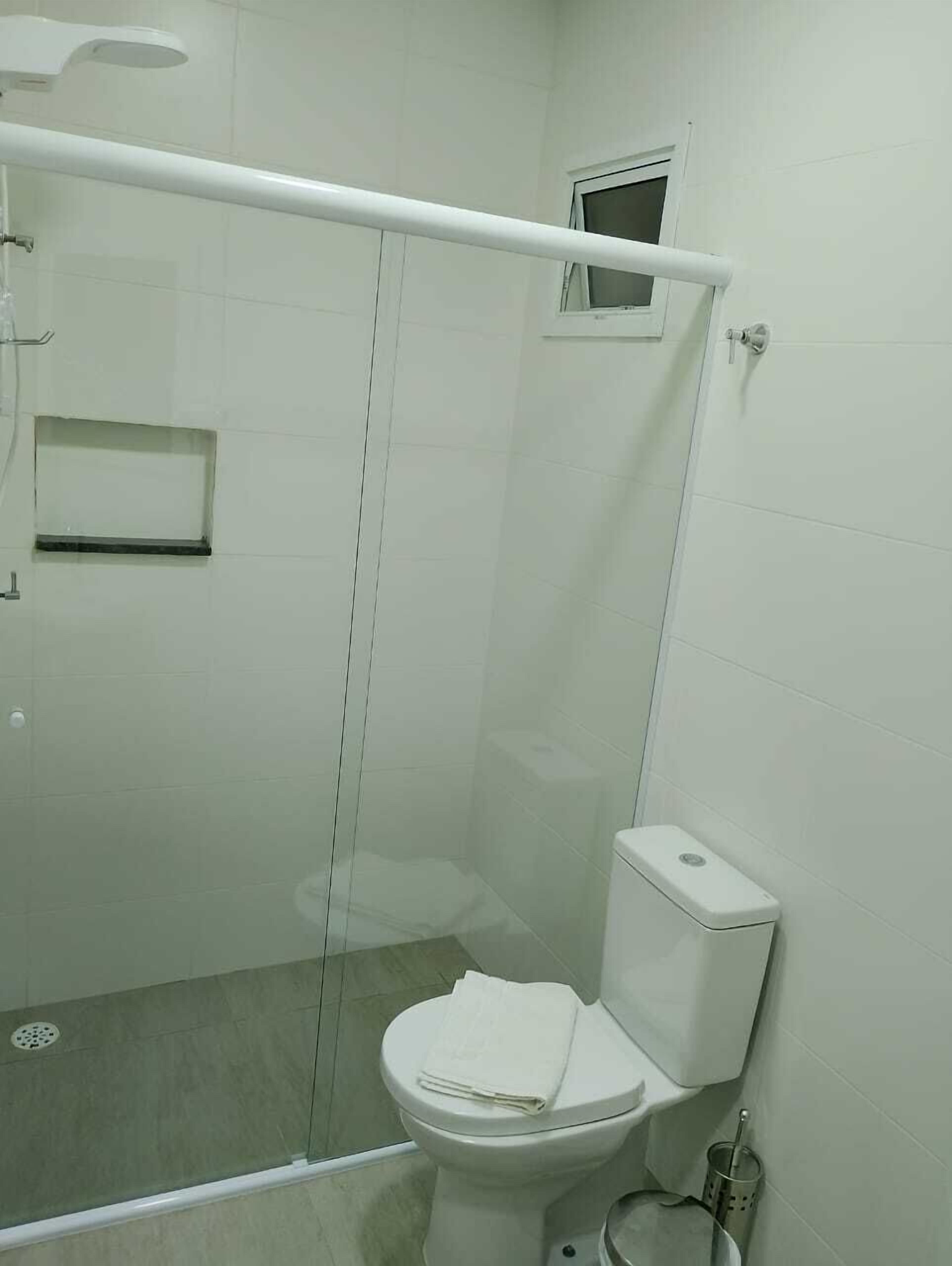 Bany amb dutxa envidriada, vàter i finestra petita.
