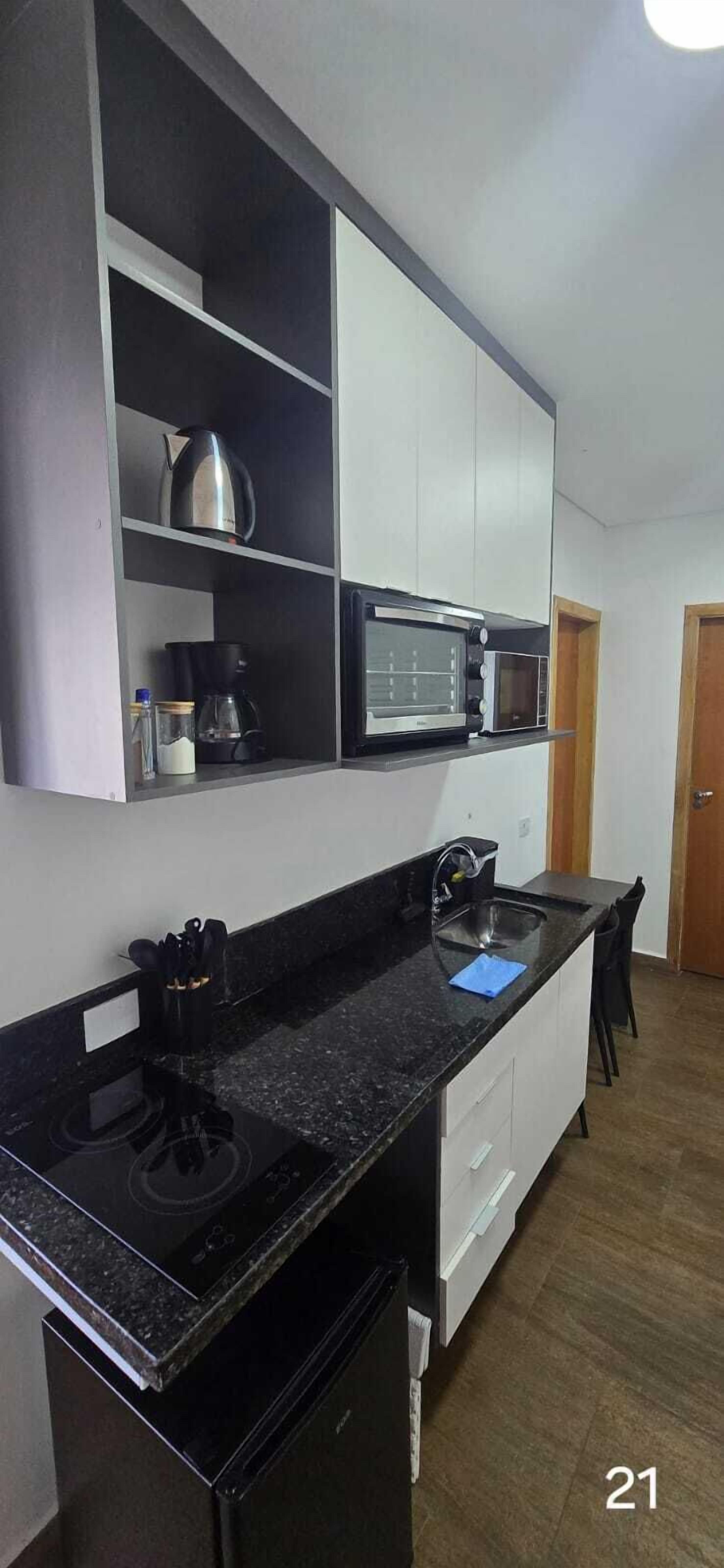 A compact kitchen with a black countertop, a built-in stove, a microwave, and a coffee maker.