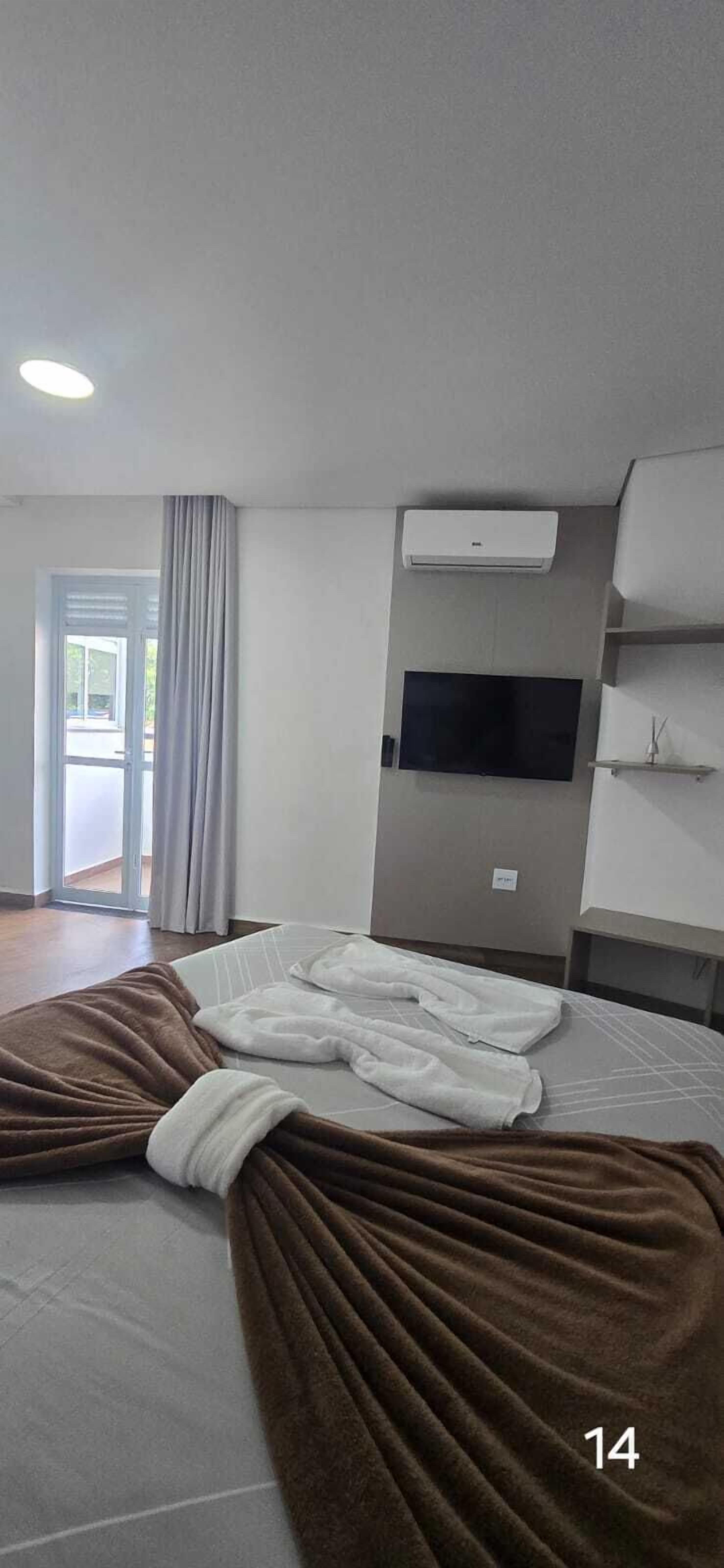 Une chambre d’hôtel équipée d’un lit, d’un téléviseur à écran plat, d’un système de climatisation et d’une porte-fenêtre coulissante donnant sur l’extérieur.