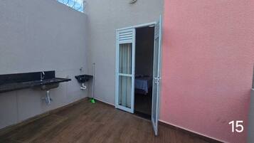Ein kleiner Balkon mit einer schwarzen Arbeitsplatte, einem Spülbecken und einer Tür, die zu einem Innenraum führt.