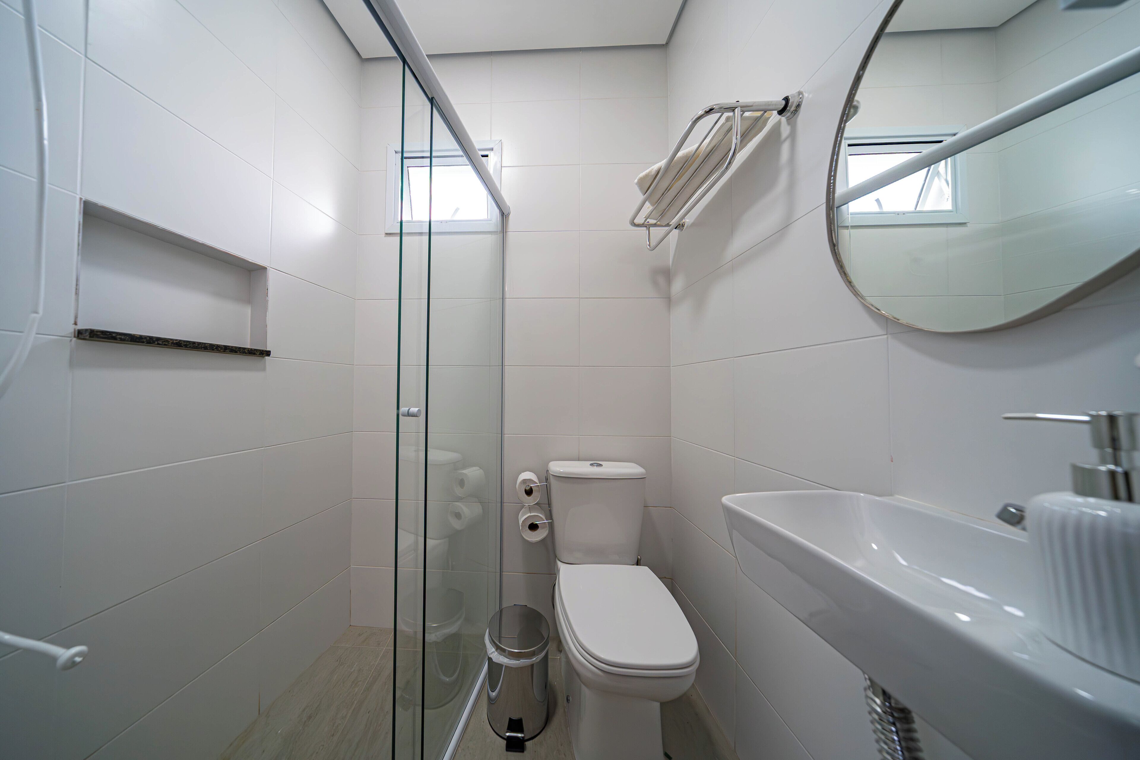 A modern bathroom with a glass shower enclosure, a toilet, and a sink.