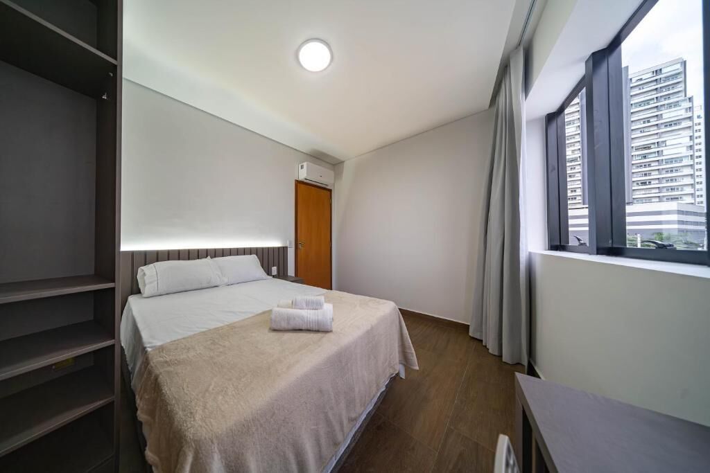 Ein Hotelzimmer mit Bett, Kleiderschrank, einem Fenster mit Vorhängen und einer Klimaanlage.