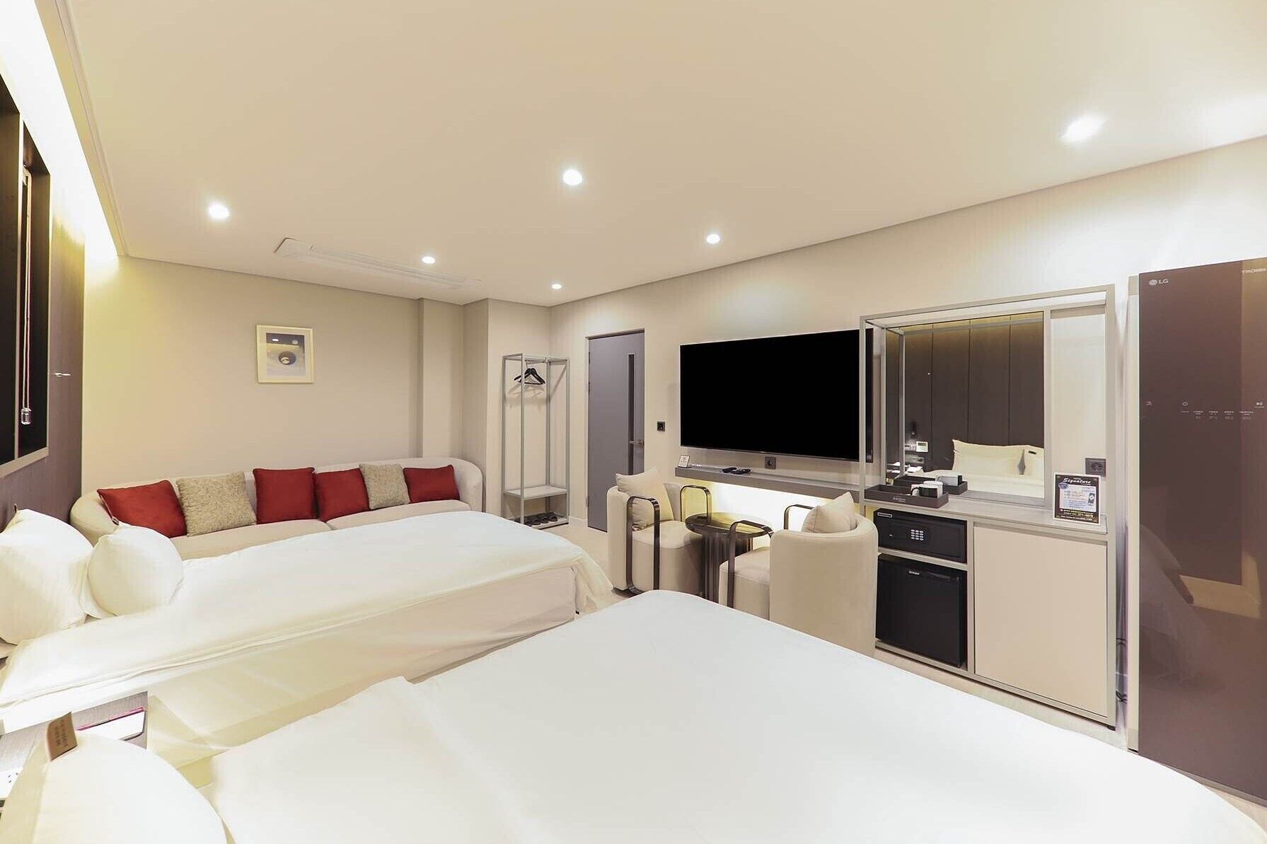 Habitación de hotel con dos camas, televisor, escritorio y armario.