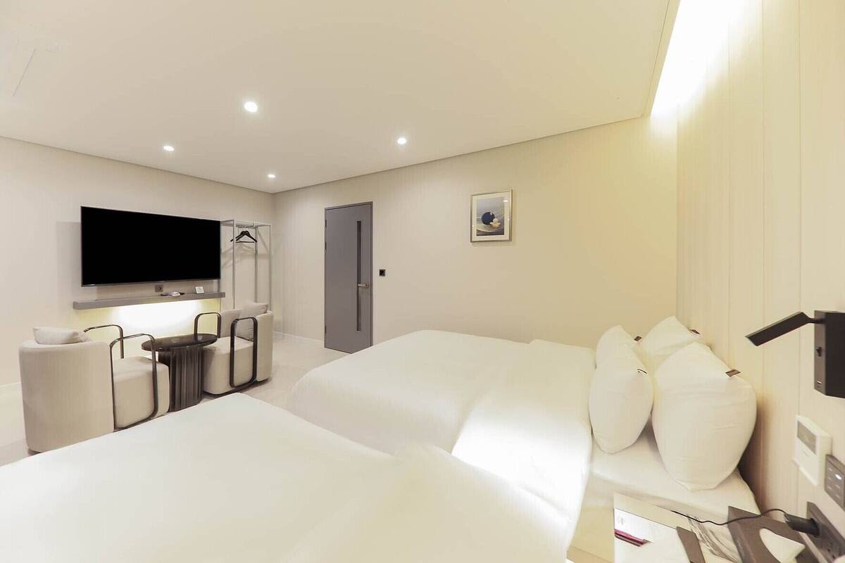 Een moderne hotelkamer met een groot bed, een bureau met stoel, een aan de muur bevestigde televisie en een deur.