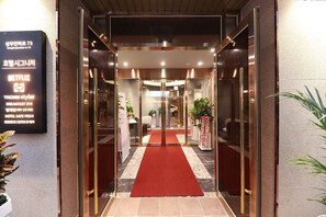 A hotel entrance with a red carpet, glass doors, and a sign listing amenities like a business center and breakfast. - HOTEL SIGNATURE GWANGJU (Gwangju)