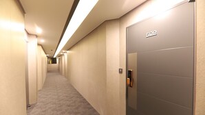 A hotel hallway with a carpeted floor, a door labeled "50", and a wall-mounted elevator control panel. - HOTEL SIGNATURE GWANGJU (Gwangju)