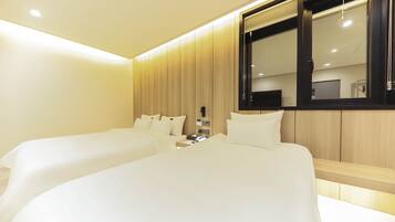 A hotel room with two beds, a wooden panel wall, a large window, and a flat-screen TV.