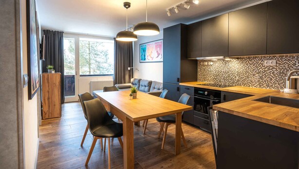 Eine moderne Küche mit einer Holztheke, dunklen Schränken und einer gefliesten Spritzschutzwand.