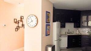 Eine Küche mit dunklen Schränken, einem weißen Kühlschrank und einer Uhr an der Wand.