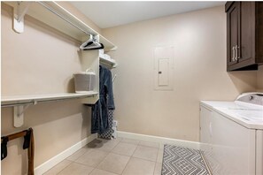 A laundry room with a washing machine, a drying rack, and a towel rack.