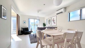 A modern living room with a dining area, large windows, and a ceiling fan.