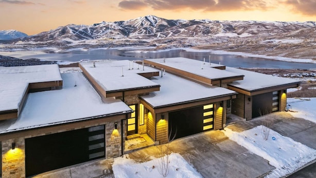 En modern byggnad med flera garageportar, ett snötäckt landskap och berg i bakgrunden.