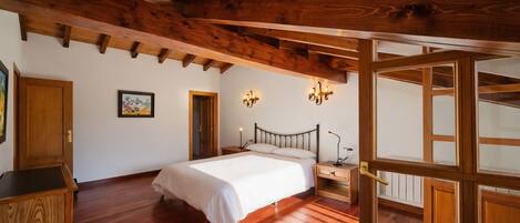 Ein Schlafzimmer mit Holzboden, einem Bett, einem Nachttisch und einer Wandleuchte.
