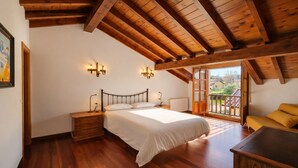 A bedroom with a wooden ceiling, a bed, a nightstand, a dresser, and a balcony with a view. - La Franca beach, garden and WiFi - Casa Freya (Franca, La)