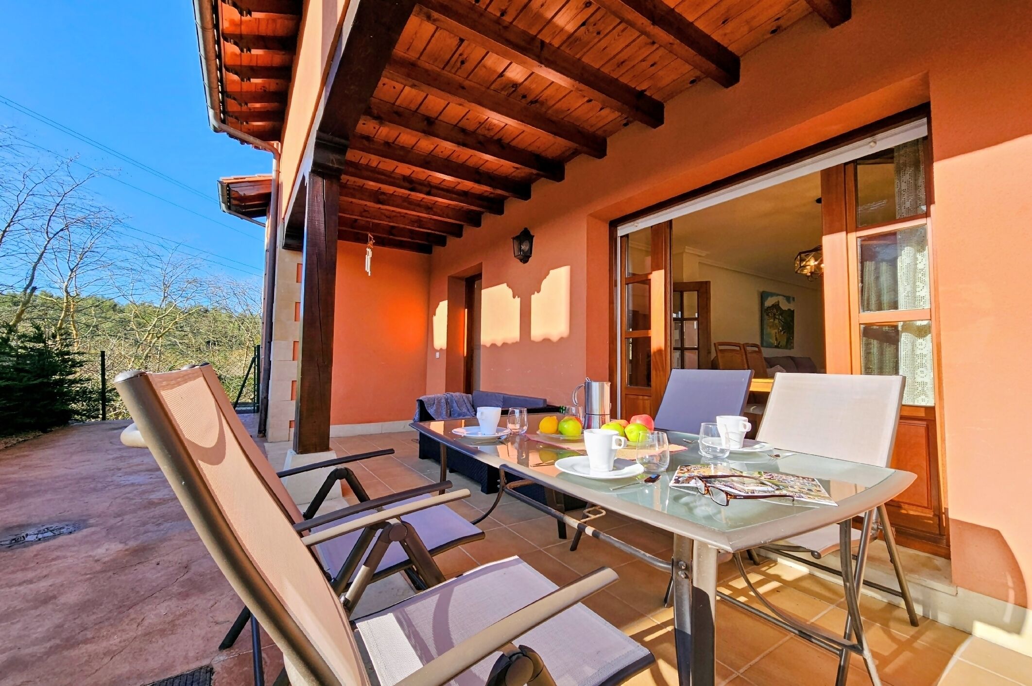 Zona pranzo con tavolo in vetro, sedie e vista sull'interno.